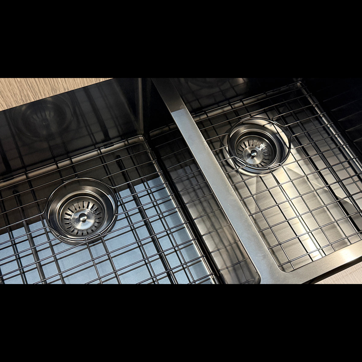 Close-up of a stainless steel kitchen sink with two round drain strainers and a grid-style drain cover.
